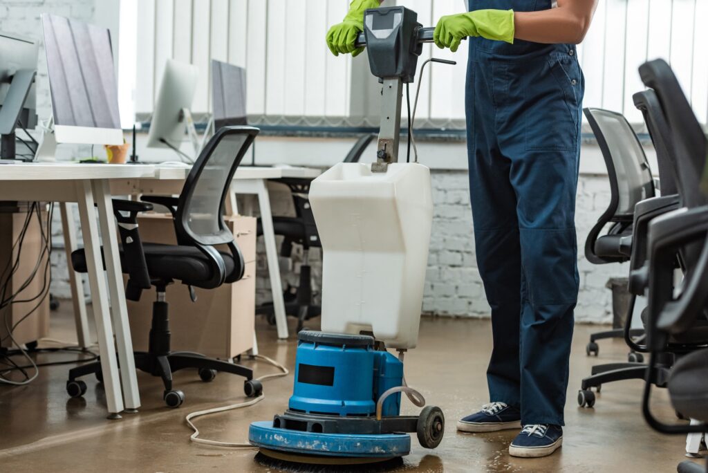 cropped view of cleaner washing floor in office with cleaning machine